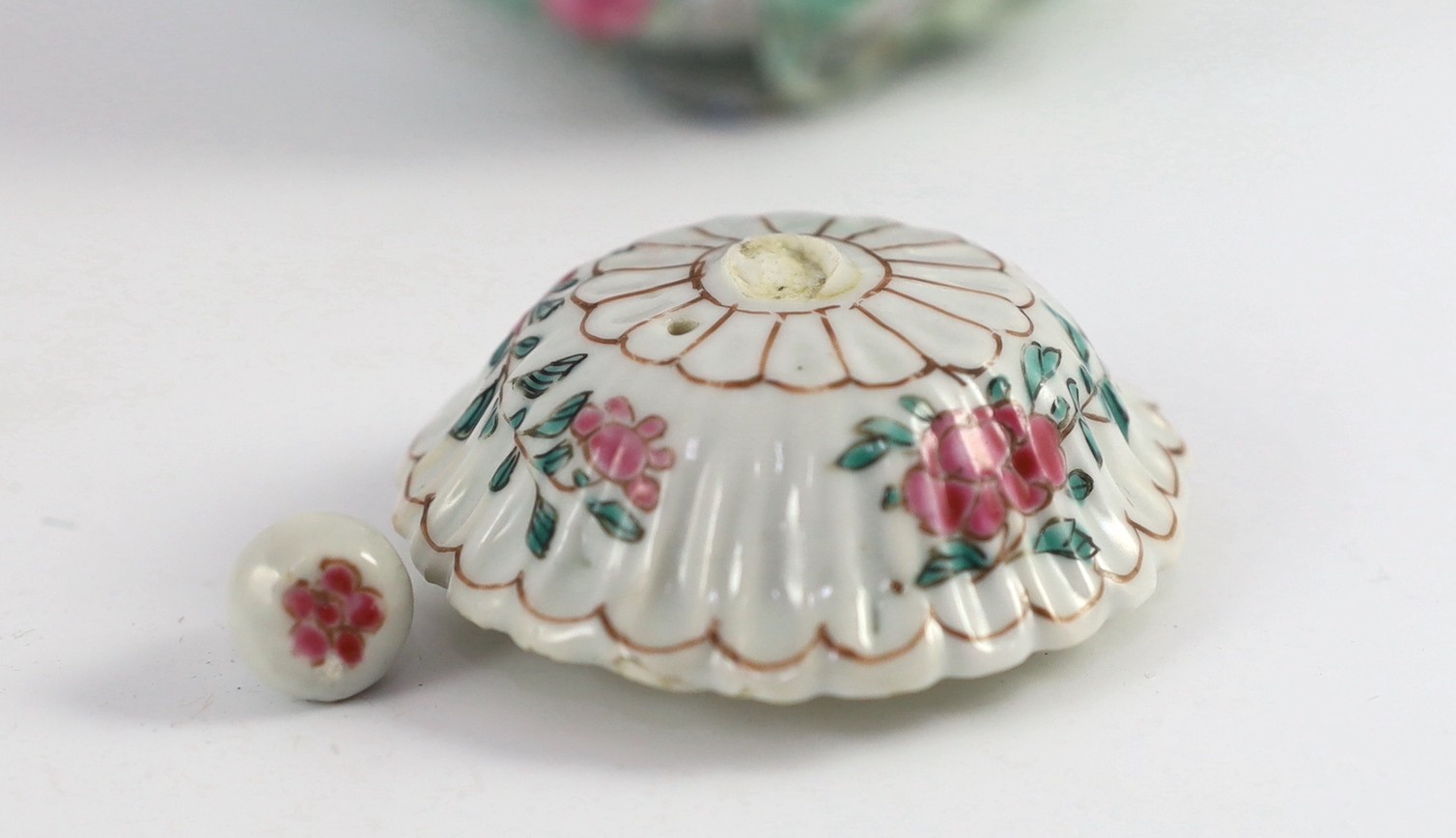 A Chinese famille rose chrysanthemum moulded teapot, early Qianlong period, painted with a cockerel amongst flowers, on a cage work base, 10 cms high